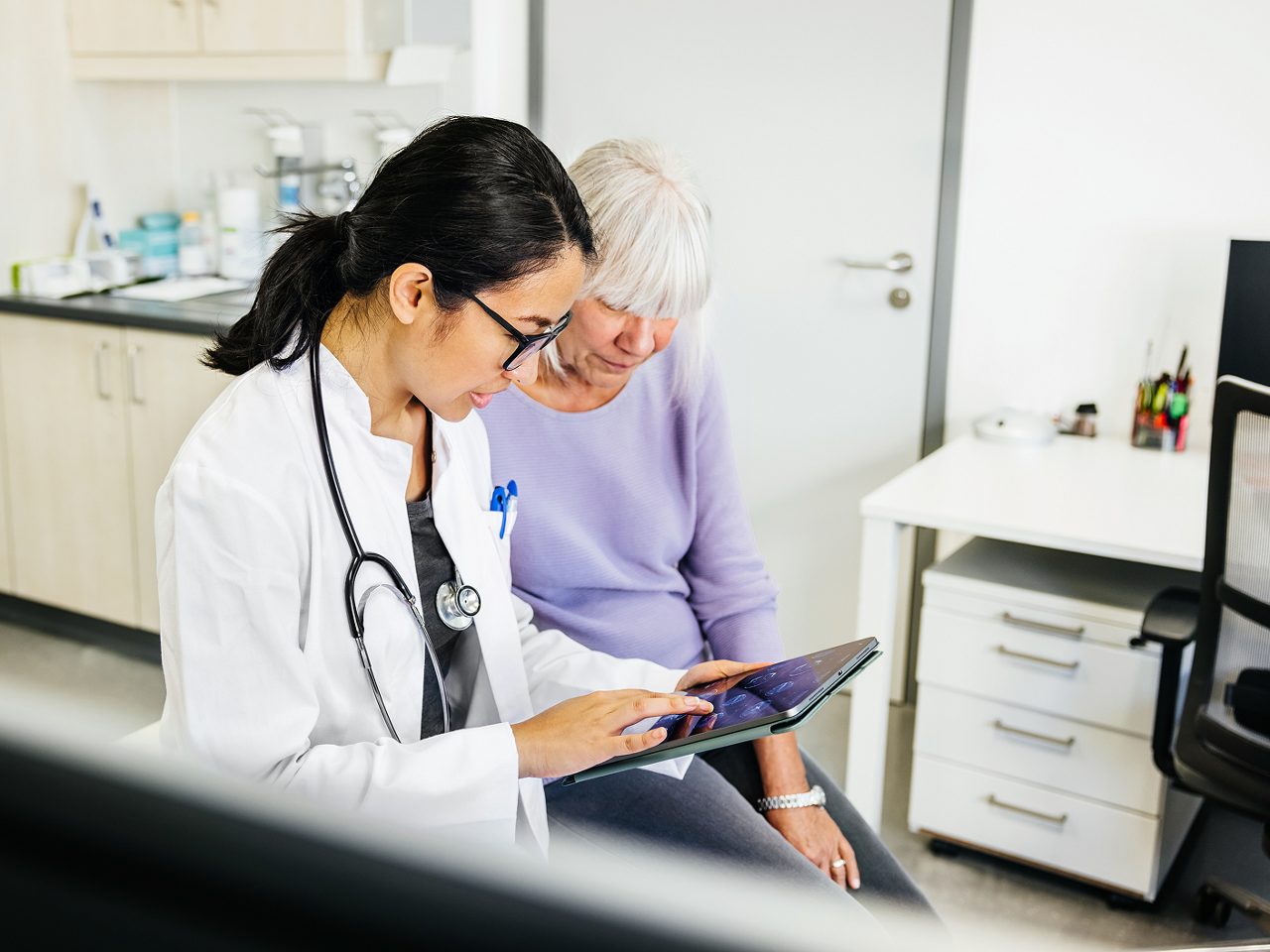 A doctor uses a tablet to discuss care with a  patient, showing Astellas’ focus on digital  health innovation.