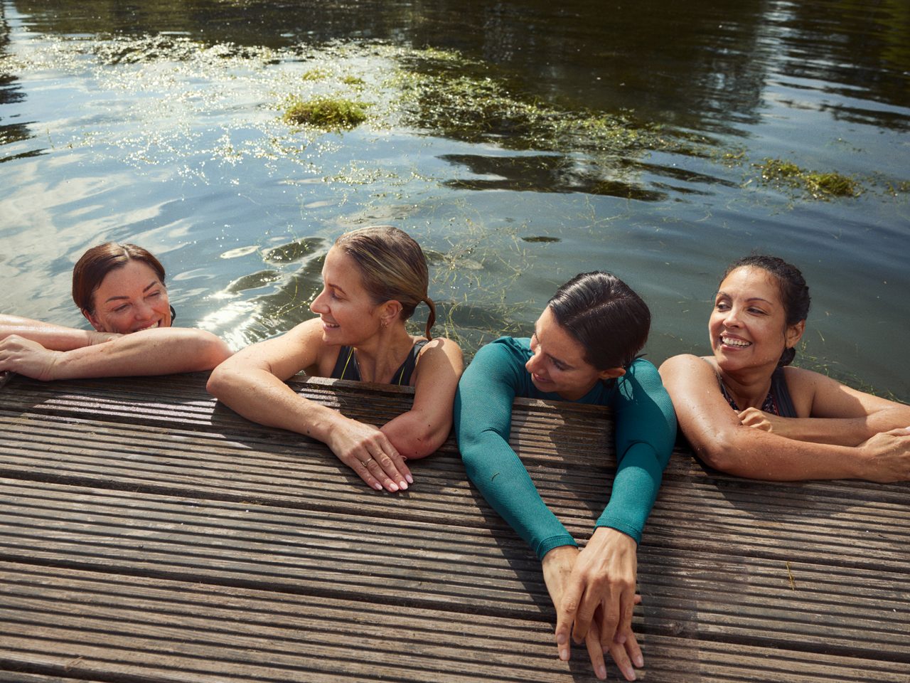 A group of diverse females in the water by a pier, symbolizing how menopause is a stage of life all women will experience and Astellas’ commitment to medical innovation.
