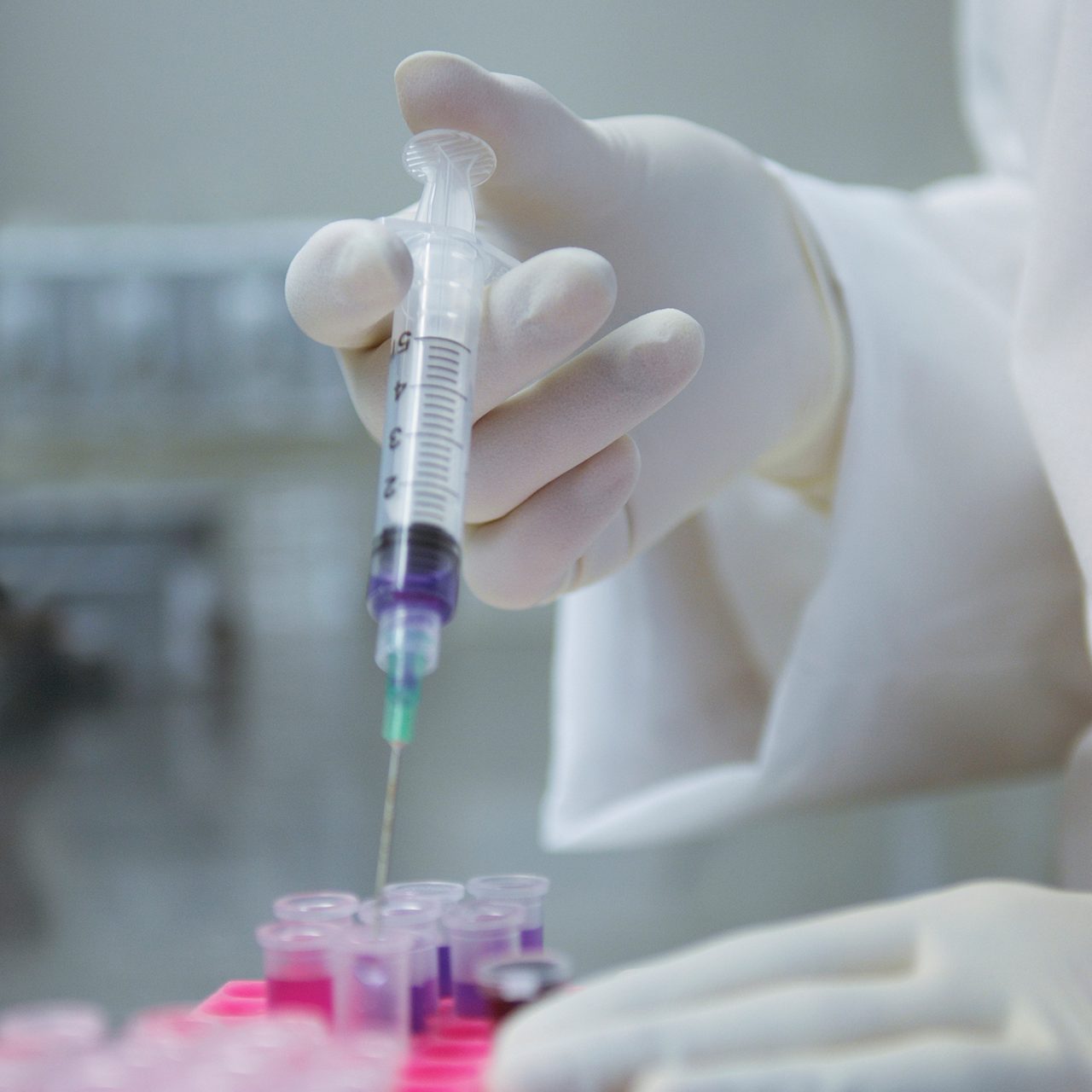 An Astellas scientist uses a syringe for tests, reflecting the company’s research-driven mission.