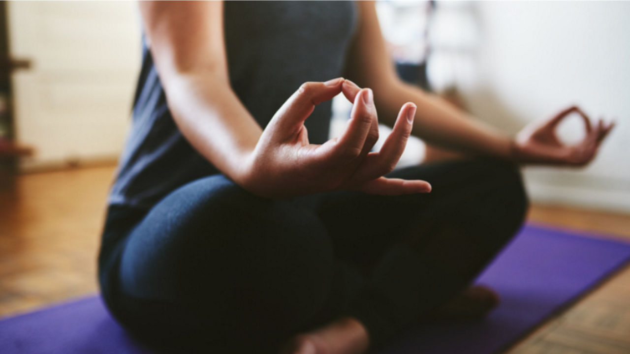 Image of a person doing yoga over a mat in the floor