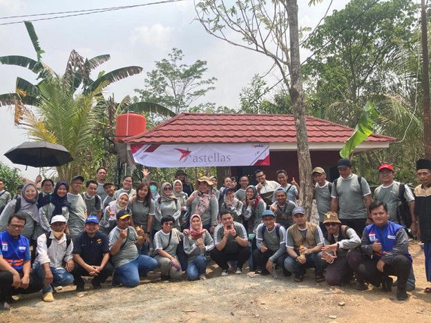 A large group of Astellas employees in Indonesia smiling for a picture while volunteering for a local community event. 