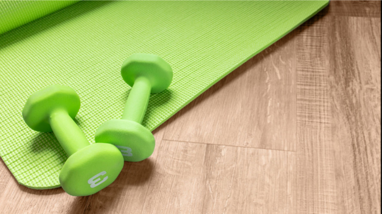 Image of a pair of green dumbbells over a green mat in the floor
