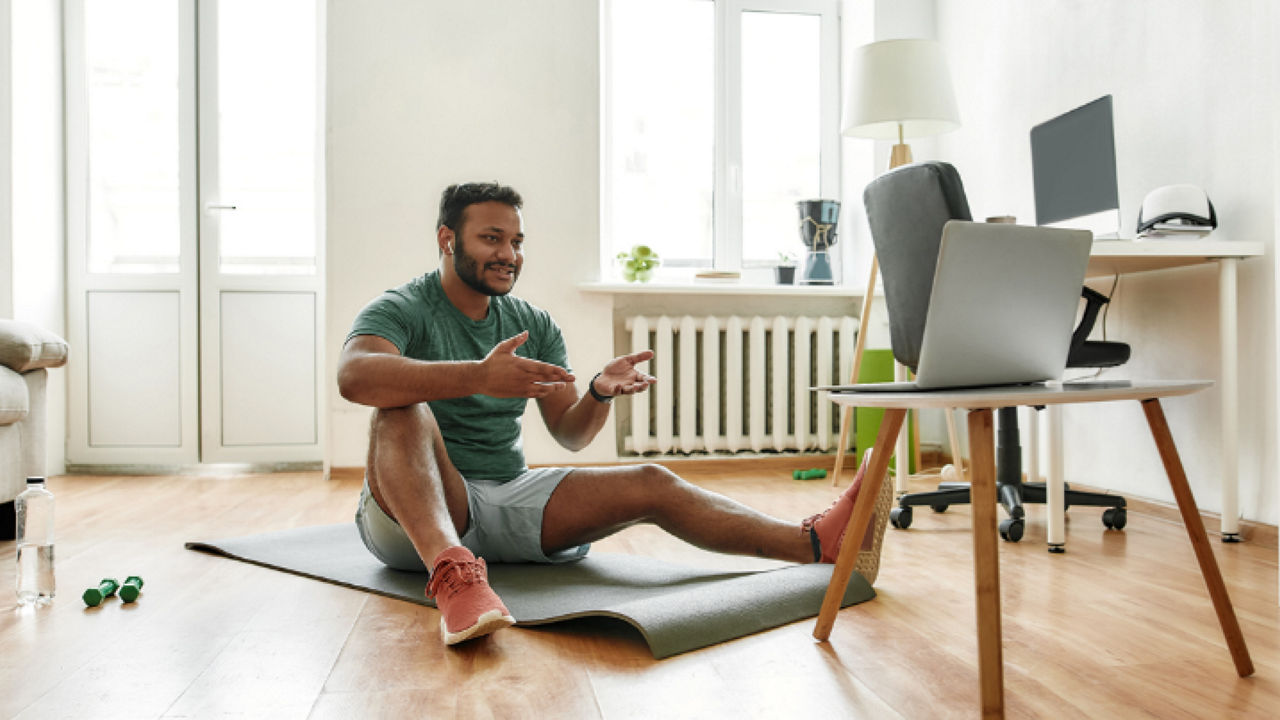 Image of a man sitting on the floor recording a fitness session