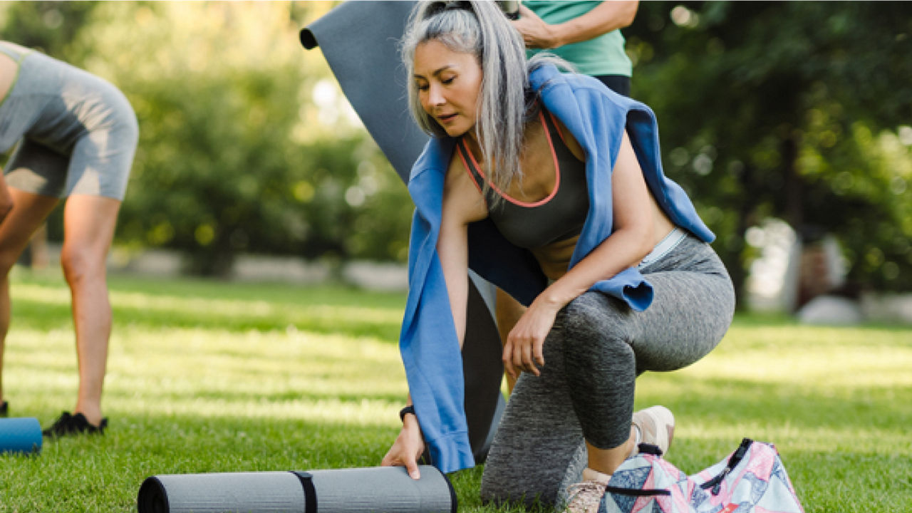 Image of a women unfolding a mat in the grass